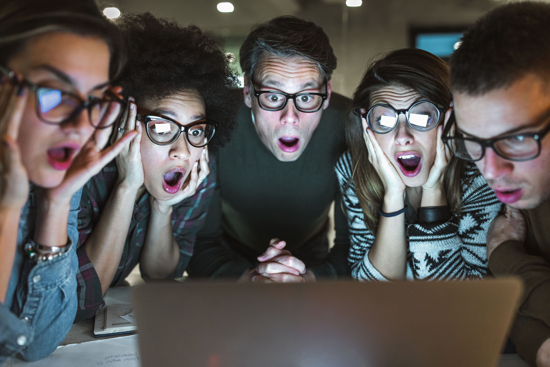 Shocked team of entrepreneurs reading an e-mail on laptop in the office.